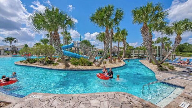 A swimming pool area with palm trees, a water slide, and lounge chairs. - 6BR Villa with Pool & Games Room, Near Disney (Davenport)