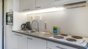 Et moderne køkken med indbygget komfur, vask og kaffemaskine.