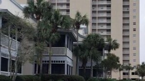 Un hôtel de grande hauteur, dont le logo est bien visible sur la façade, entouré de pelouses bien entretenues et de palmiers.
