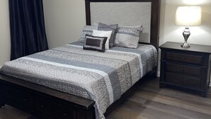 Una camera da letto con un letto di legno, un comodino, una lampada e una tenda scura.
