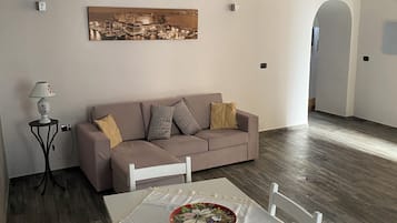 A living room with a sofa, a dining table with a bowl, and a lamp.