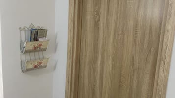Una porta di legno con maniglia e serratura in metallo, e a lato una mensola in metallo con oggetti decorativi.