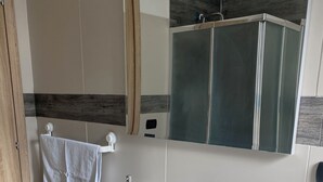 Ein modernes Badezimmer mit einem weißen Waschbecken, einem Spiegel und einer Holztür.