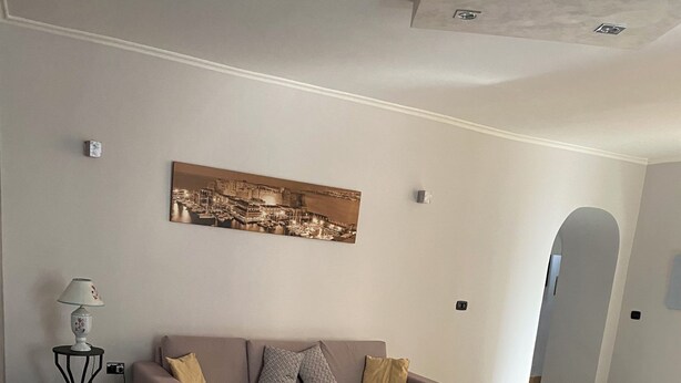 Ein Essbereich mit einem weißen Tisch und Stühlen, einer Couch mit Kissen, einer Lampe und einem Gemälde an der Wand.