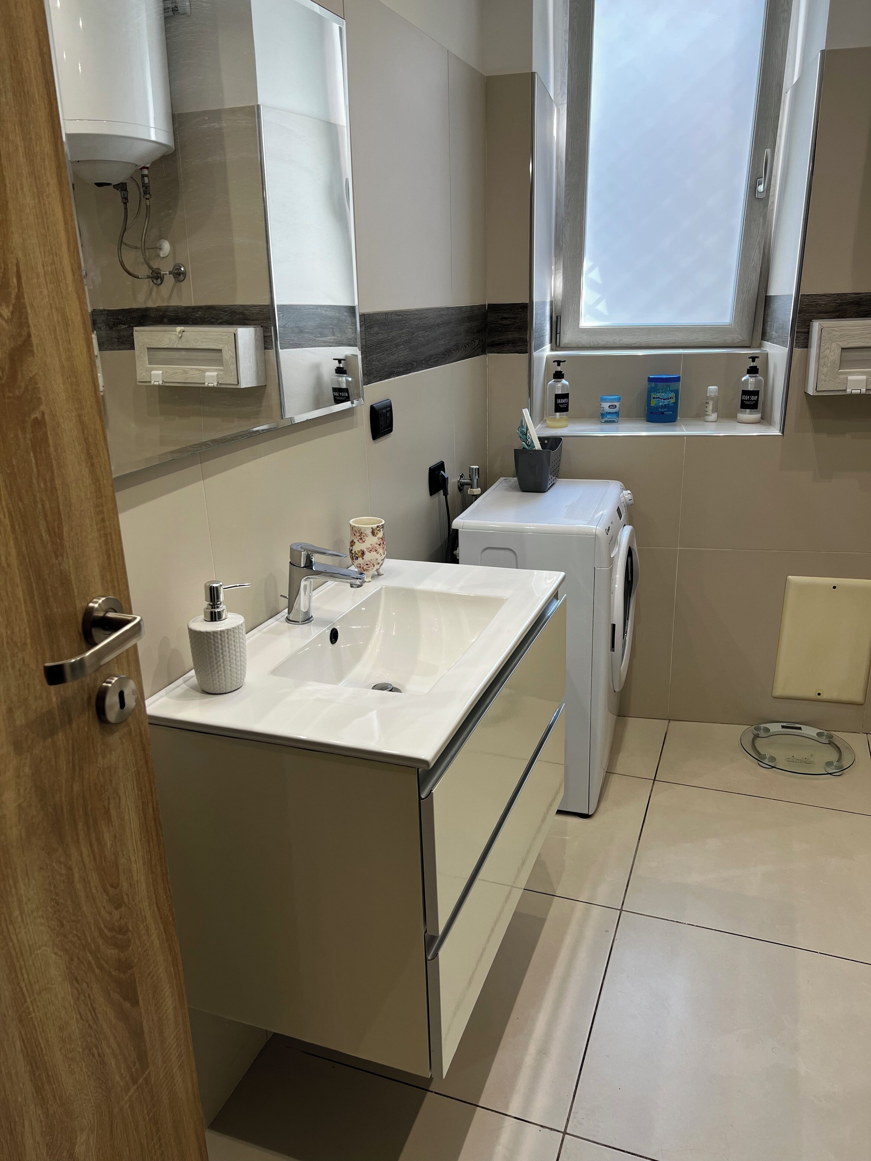 Ein modernes Badezimmer mit Waschbecken, Spiegel und integriertem Waschvollautomat.