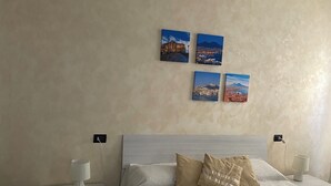 Ein Hotelzimmer mit einem Bett, zwei Nachttischen, einer Lampe und drei Bildern an der Wand.