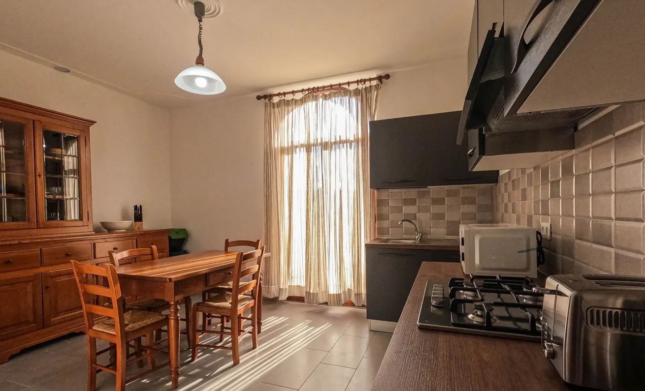 Una cocina con una mesa de comedor, sillas, estufa y microondas.