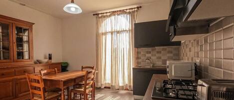 Una cocina con una mesa de comedor, sillas, estufa y microondas.