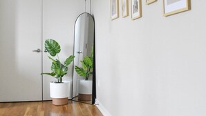 Una habitación amplia con piso de madera, una puerta blanca y una pared decorada con cuadros.