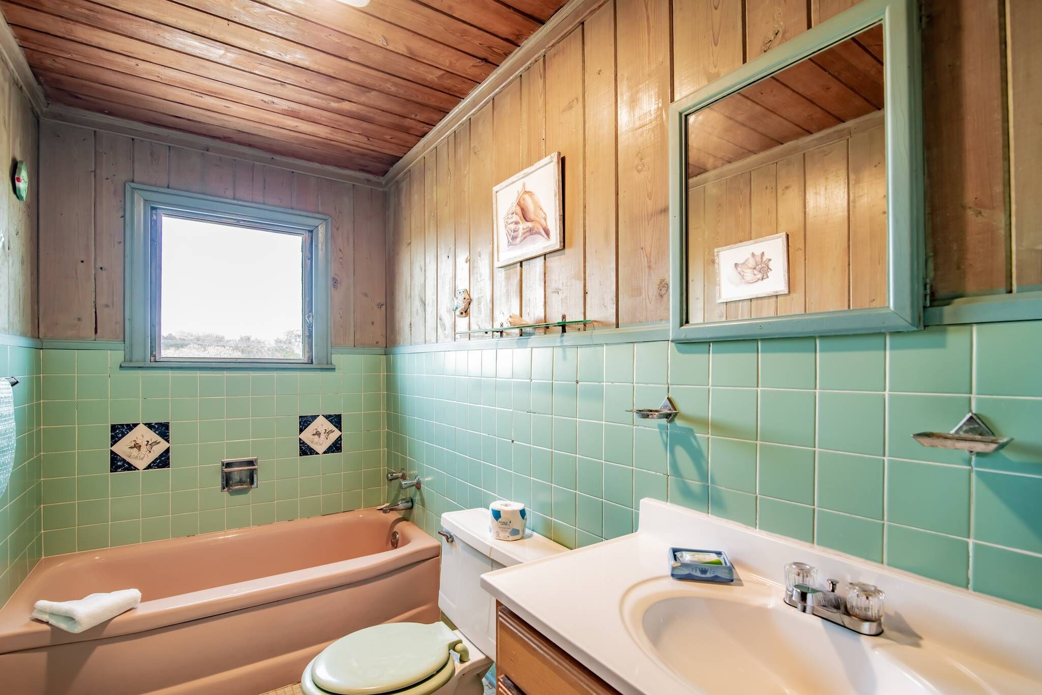 Une salle de bain avec un plafond en bois, une baignoire, des toilettes et un lavabo.