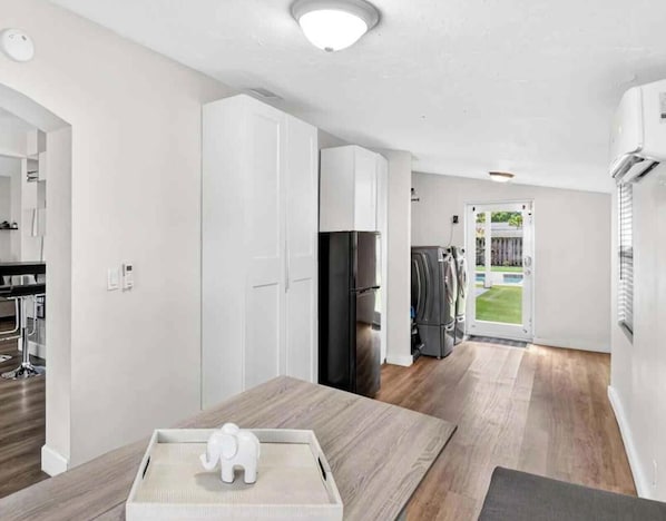 Una cocina moderna con armarios blancos, un refrigerador negro y un comedor con mesa de madera y una figurita decorativa de elefante.