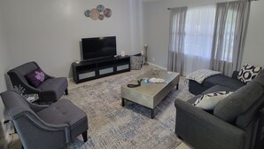 A living room with a ceiling fan, a flat-screen TV, and a sofa set. - Family-friendly, Less than 5 minutes from Kings Bay, water park huge backyard.
 (St. Marys)