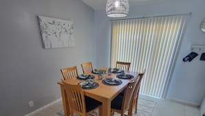 A dining area with a wooden table set for four, surrounded by chairs, a patterned rug, and a ceiling light fixture. - Family-friendly, Less than 5 minutes from Kings Bay, water park huge backyard.
 (St. Marys)
