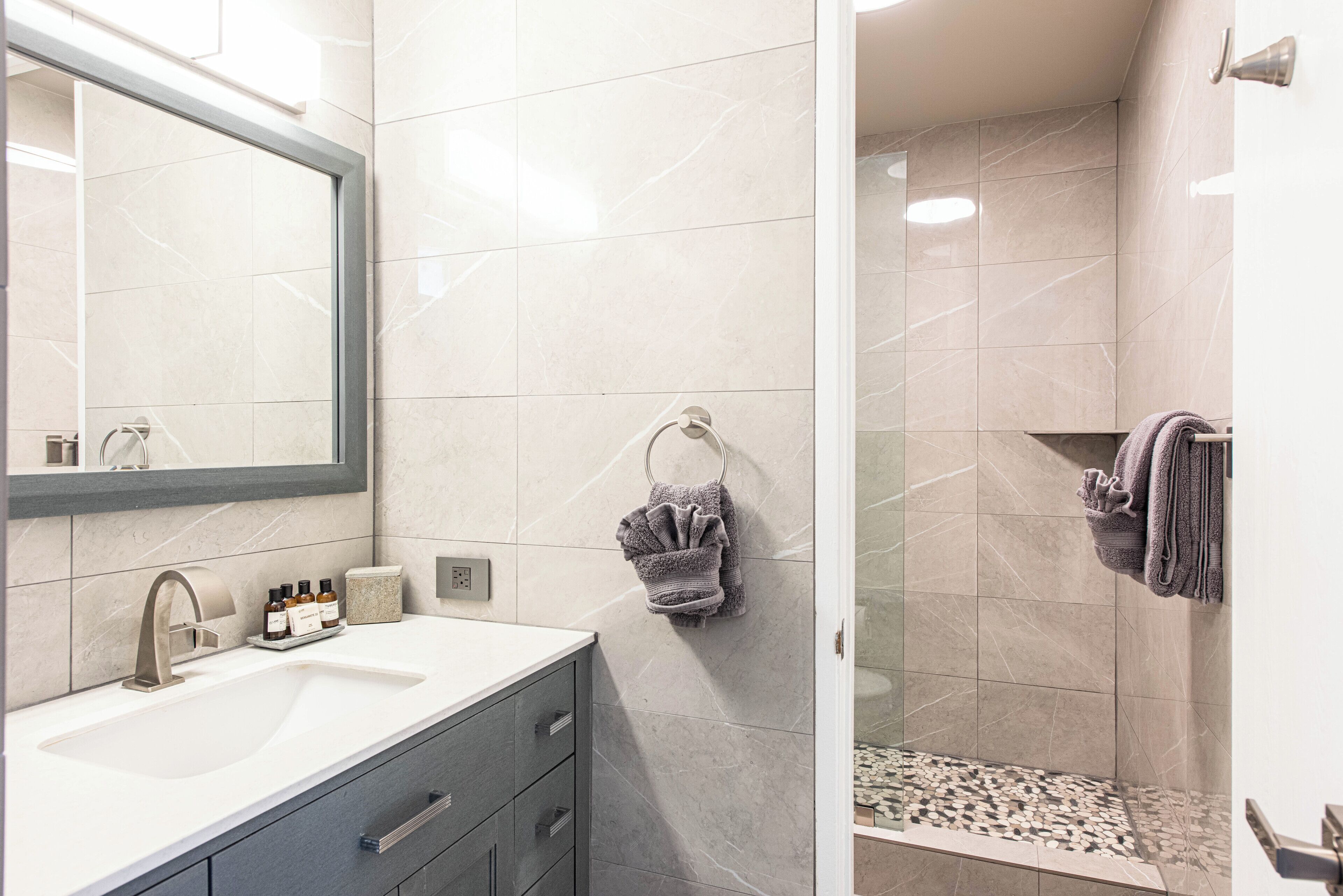 Une salle de bain moderne avec un lavabo, un miroir et un espace douche.