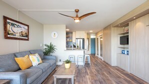 Un salon moderne avec un canapé gris, une table basse en bois et un ventilateur de plafond.