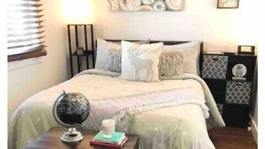 Un dormitorio con cama, mesita de noche, lámpara y un adorno en la pared.