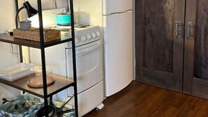 Una cocina con una estufa blanca, un refrigerador blanco y una puerta de madera.