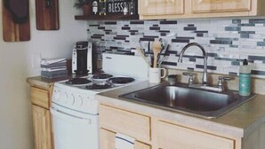 Una cocina con armarios de madera, una estufa, un lavamanos y un salpicadero con un cartel que dice 'Grateful, Thankful, Bless'.