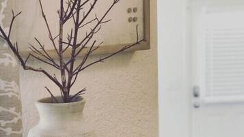 A vase with a branch on a shelf, a framed sign with the words "LOVE LIFE", and a candle in a jar on a tray.