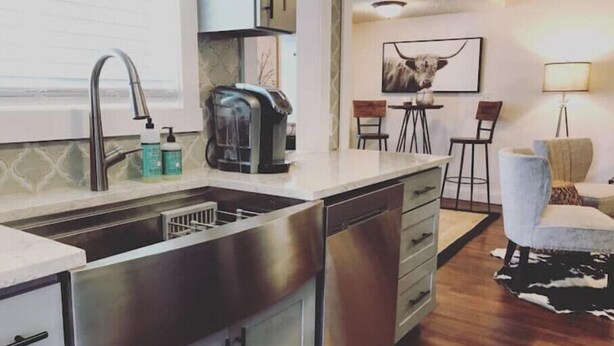 A compact kitchen with a stainless steel sink, a coffee maker, and a small dining area with a table and chairs.