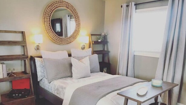 A neatly arranged bedroom with a bed, bedside tables, a mirror, and a small table with a candle. - Cut Bank Studio #6 near Glacier National Park (Cut Bank)