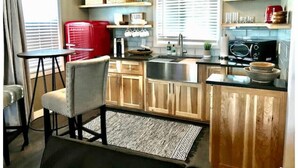 A compact kitchen with wooden cabinets, a red appliance, and a 'let's eat' sign. - Cut Bank Studio #6 near Glacier National Park (Cut Bank)