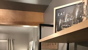 Eine kompakte Küche mit Essbereich, ausgestattet mit einer Holz Arbeitsplatte, einem kleinen runden Tisch und einem Stuhl.