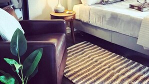 Een hotelkamer met een bed, twee bedlampen, een kleine tafel, een stoel en een plant.