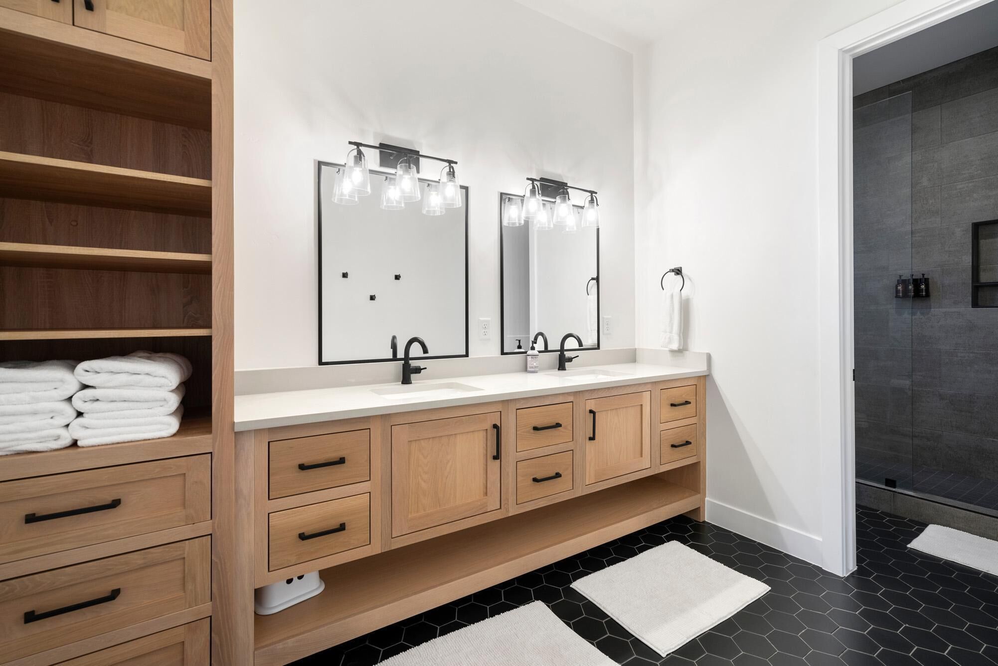 Une salle de bain moderne avec un double vasque, des meubles en bois et un grand miroir avec éclairage intégré.
