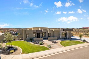 A modern two-story house with a stone facade, a driveway, and landscaped lawn. - Exclusive Pool Villa (St. George)