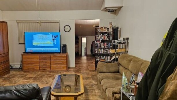 A living room with a television, wooden furniture, a sofa, and a bookshelf. - Chena marina guest apartment.  (Fairbanks)
