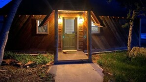 A rustic cabin with a wooden exterior, a front porch, and a door with two windows.
