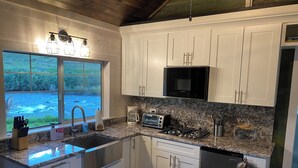 A modern kitchen with white cabinets, a stainless steel sink, a microwave, a toaster, and a coffee maker.