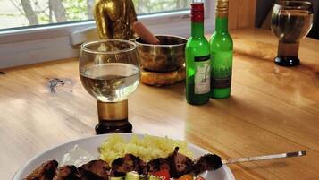 A dining table with a Buddha statue, a bowl, a plate of food, and two bottles of wine.