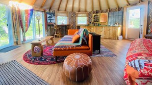 Acogedor interior de una yurta con sofá, reposapiés y una mesita.