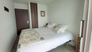 A bedroom with a bed, a wardrobe, and a small bedside table. - T2 moderne avec vue bassin – 4 couchages (ARCACHON)