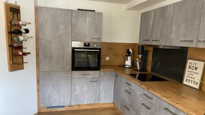 Uma cozinha moderna com armários cinzas, bancada de madeira e forno embutido.
