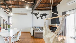 A modern interior with a wooden ceiling, a world map on the wall, a hammock, a sofa, and a dining area with chairs. - GuestHost - Vucciria Central Flat with Small Terrace (Palermo)