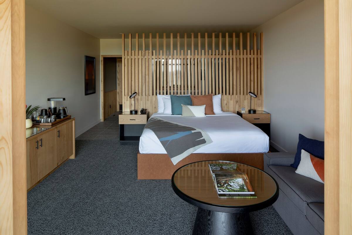 Une chambre d’hôtel avec un lit, des tables de chevet, un canapé, un coin café et une petite table avec un livre.