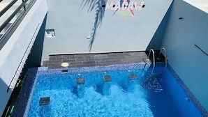 A swimming pool with a tiled deck and a metal ladder. - Villa Boho Chic (Juan Dolio)