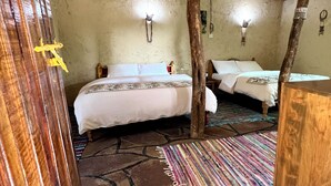 Ein rustikales Zimmer mit einem Bett, einer Holztür und einem farbenfrohen Teppich.