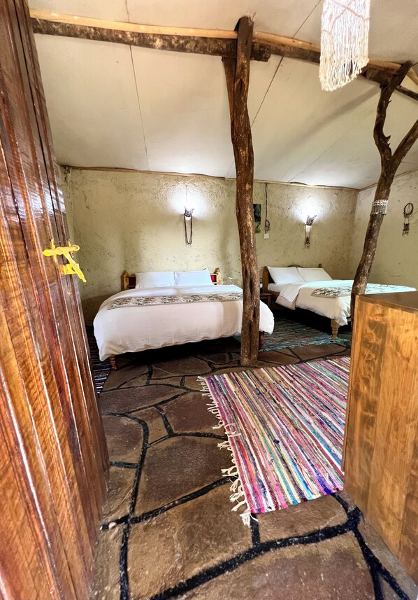 Een eenvoudige kamer met een bed, een houten deur en een kleurrijk vloerkleed.