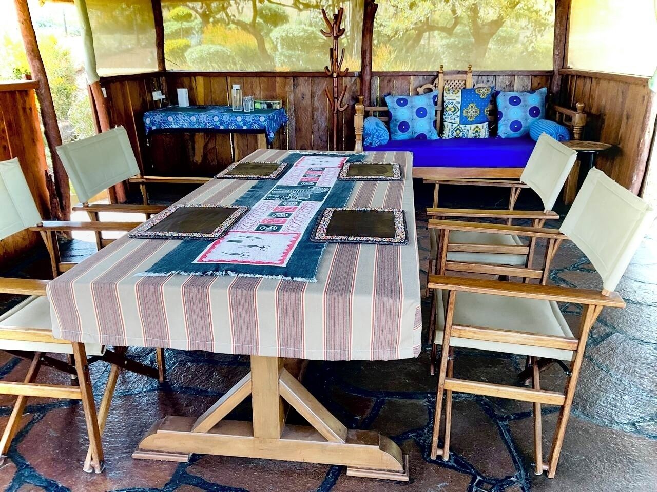 Un tavolo da pranzo in legno con una tovaglia a righe, circondato da quattro sedie con sedili imbottiti.