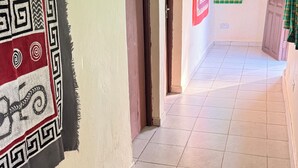 Ein Flur mit einem Wandbehang mit Muster, einer Tür und einem Fenster mit kariertem Vorhang.
