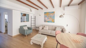 A modern living room with a sofa, coffee table, and dining table. There is a ladder against the wall and a painting above the sofa. - cozy house close to the beach with garden (Saladillo Benamara)