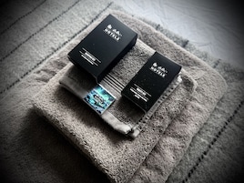 Two black boxes labeled "Sleeping Set" and "Vanity Kit" on a textured gray towel.