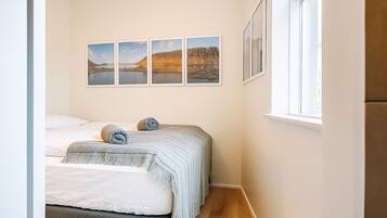 Un dormitorio con dos camas, una ventana y cuatro cuadros en la pared.