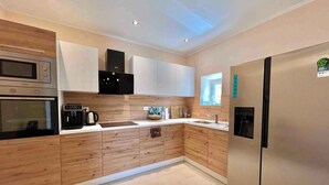 Eine moderne Küche mit Holzausstattung, Edelstahlgeräten und Fliesenboden.