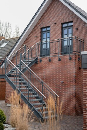 A brick building with a metal staircase leading to a second-floor window. - Altstadtdomizil Wohnung Helin - Pure Entspannung in der Altstadt Borkums! - Alte Schulstraße (Borkum)
