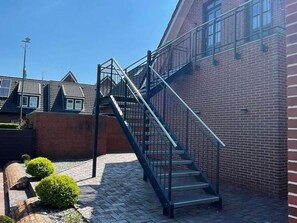 Una escalera metálica conduce a un edificio de ladrillo bajo un cielo despejado.